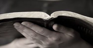 a picture of two hands holding and reading the bible